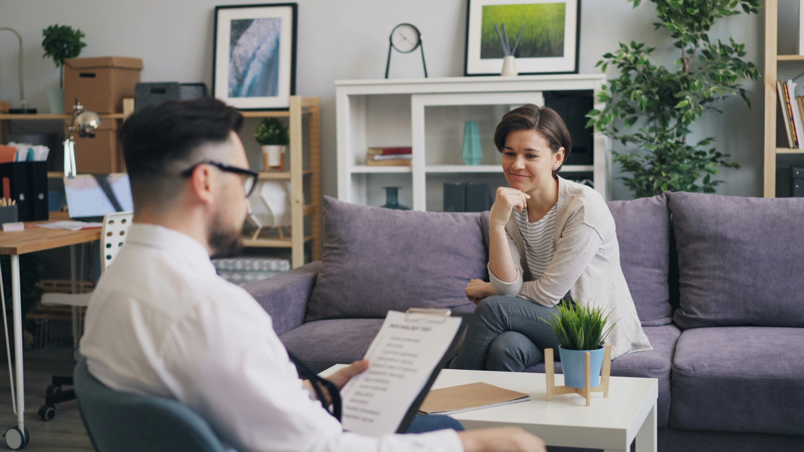 Male therapist with clipboard in session with smiling female patient at Psych Pointe mental health clinic in DFW Texas